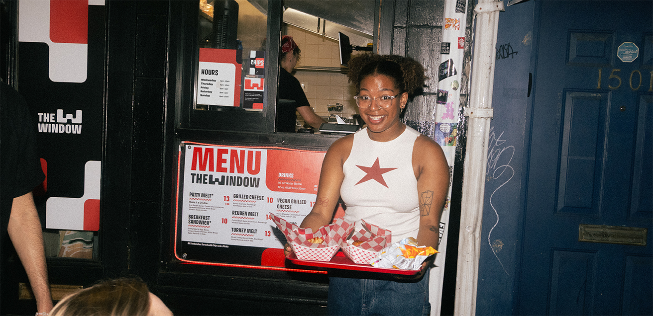 A customer bringing their food to a table surrounded by people.