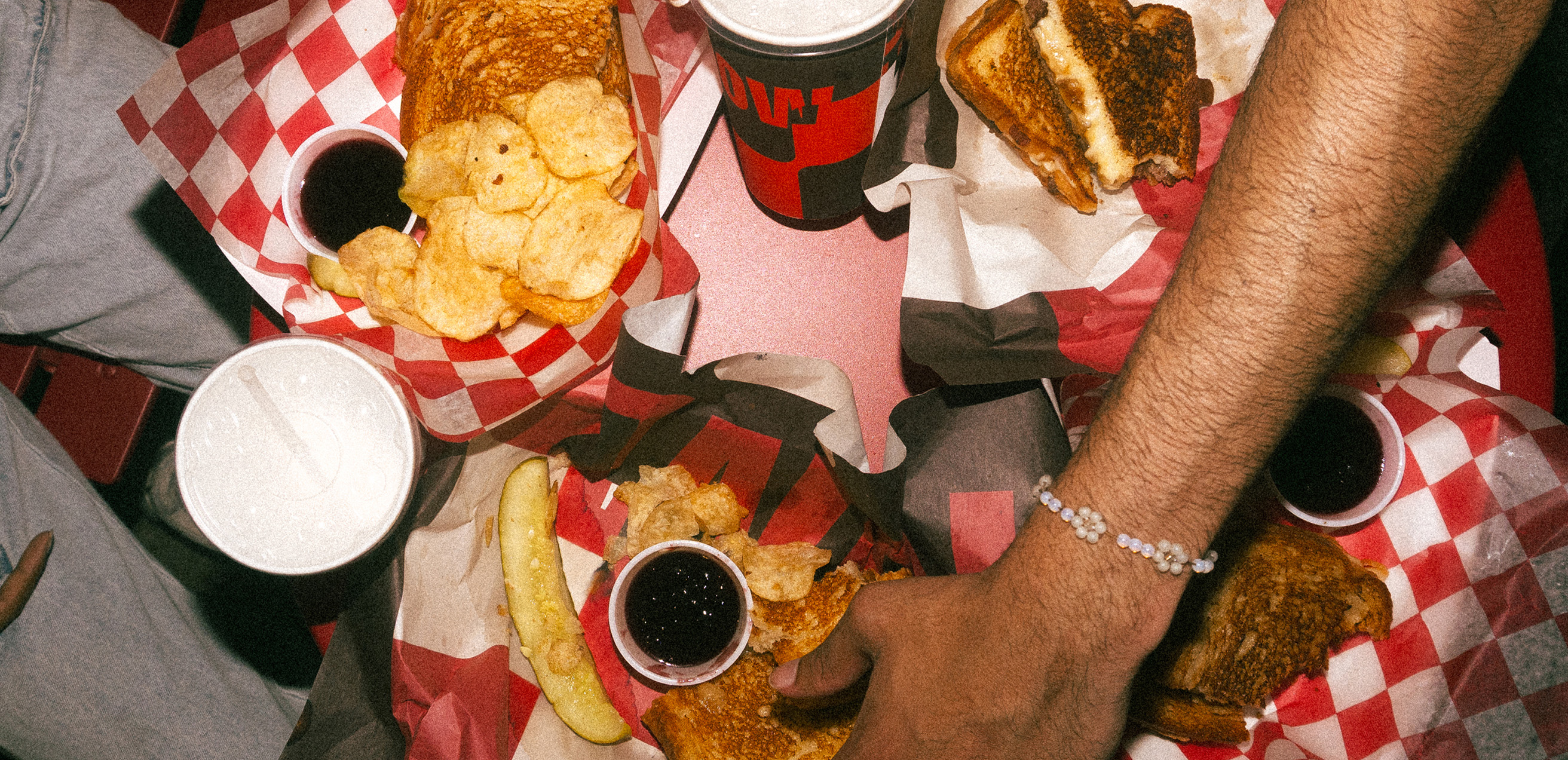 Tabletop image with various sandwiches and drinks on the table.